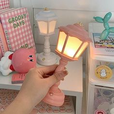 a person is holding a small light on a table with other items in the background