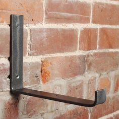 a brick wall with a metal hook on it's side and a red brick wall in the background