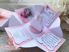 a pink and white wedding card with an angel on the front, in a box next to flowers