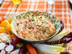 a bowl filled with food sitting on top of a table next to vegetables and crackers