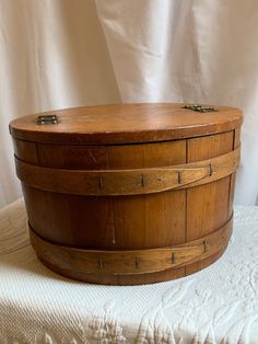 an old wooden basket sitting on top of a white bed cover covered by a white sheet