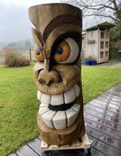 a large wooden statue sitting on top of a wooden table next to a green field