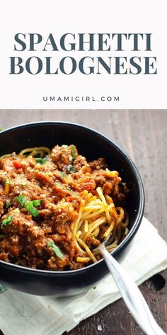 spaghetti bolognesee in a black bowl with a spoon and napkin next to it