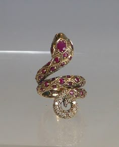 A stunning 9ct solid gold real ruby & diamond coiled snake ring the front of the coiled snake is fully set with quality round cut rubies with a larger oval cut ruby to head. the tip of tail is set with 32 real round cut diamonds. the double back band is designed with snake scales engraved in the gold. front measures 3.5cm high, sits around finger & very comfortable to wear. ring size uk-n, usa6.75. stamped 9ct. looks stunning when worn. box for display only will come boxed. Snake Gold Ring, Snake Engagement Ring, Luxury Wedding Snake Ring With Gemstone, Snake Jewellery, Snake Ring With Stone, Luxury Gold Unique Snake Ring, Luxury Formal Gemstone Snake Ring, Luxury Unique Gold Snake Ring, Luxury Gold Snake-shaped Ring