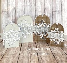 three snowflaked tags are sitting on a wooden table with the words, holiday card