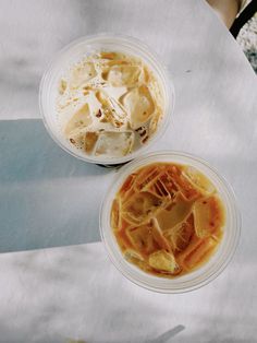 two plastic bowls filled with food sitting on top of a white tablecloth covered table