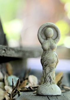 an old statue is sitting on the ground in front of some leaves and twigs,