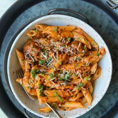 a bowl filled with pasta covered in sauce and parmesan cheese next to a fork