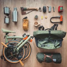 an assortment of tools laid out on a wooden floor next to a bicycle and backpack