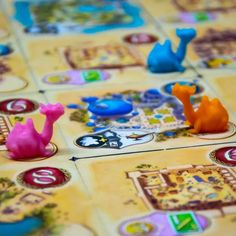 a board game with several small plastic animals on it's boards, including one pink and one blue