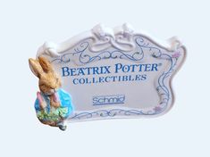 a ceramic sign that says beattrix potter collectibles with a rabbit figurine