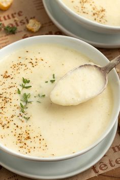 two white bowls filled with soup on top of a table