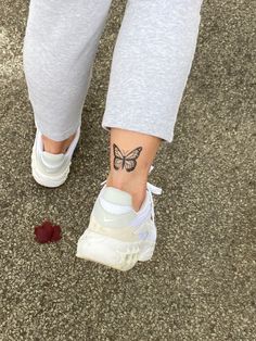 a woman's foot with a butterfly tattoo on her left ankle and white sneakers