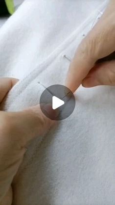 someone is sewing something on top of a white blanket with their hands and thumbnails