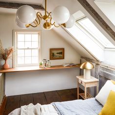 a bed sitting under a window in a bedroom next to a wooden table and chair