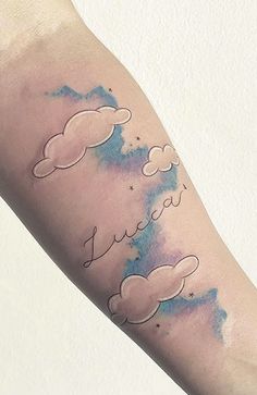 a person with a tattoo on their arm that has clouds and stars painted on it