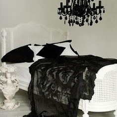 a black and white photo of a bed with a chandelier