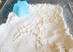 a glass bowl filled with white flour and a blue spatula on top of it