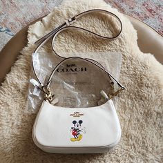 Adorable New With Tags Disney X Coach Mickey Mouse Leather Teri Shoulder Or Crossbody Bag Is In Excellent New Condition. Gorgeous Chalk Soft Pebbled Leather With Brilliant Colorful Mickey Mouse On Front, And Brass Logo Badge And Hardware. Top Zipper Closure With 1 Open Pocket On One Side, And 2 Credit Card Slots On Sidewall On The Opposite Side. All Packing Materials And Tags, Along With Crossbody Strap Are Included. It Measures Approximately 9 3/4" By 5 3/4". A Super Adorable Bag That Would Make A Wonderful Gift! From Non-Smoking Home. Mochila Coach, Coach Mickey Mouse, Minnie Mouse Purse, Mickey Mouse Bag, Glitch Mode, Coach Disney, Disney Purse, Girly Bags, Logo Badge