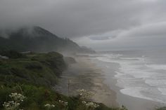 the beach is covered in fog and low lying clouds as it sits next to the ocean