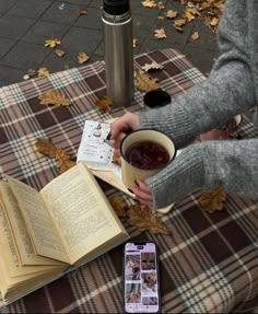 an open book sitting on top of a table next to a cup of coffee and cell phone