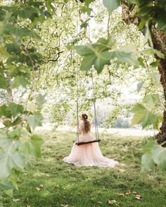 a woman sitting on a swing in the grass