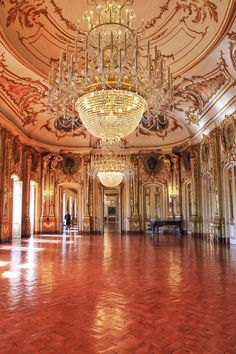 an ornate ballroom with chandeliers and red tile flooring is seen in this image