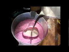 a pink liquid is being poured into a blender and then stirred with a spoon