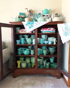 a cabinet filled with lots of teal colored dishes and cups on top of it