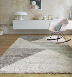 a white chair sitting on top of a wooden floor next to a gray and white rug