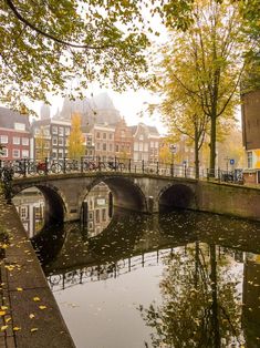 a bridge over a small river in the middle of a city with buildings on both sides