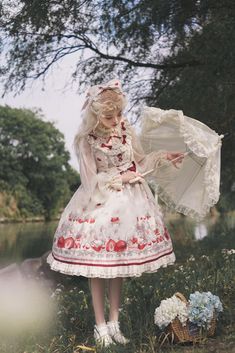 a woman in a white dress holding an umbrella next to a body of water and trees