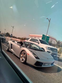 two white sports cars driving down the road