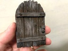 a hand holding a small wooden door that is made to look like it's inside