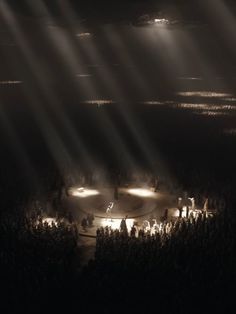 a group of people standing on top of a lush green hillside under bright beams of light