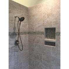 a walk in shower sitting next to a tiled wall and floor covered in gray tiles