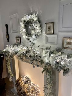 a fireplace decorated for christmas with white flowers and greenery