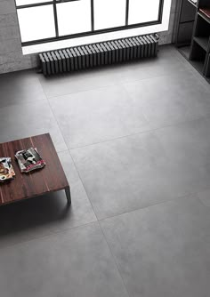 a coffee table sitting on top of a gray floor next to a book shelf and window