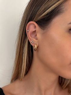 a close up of a woman's ear with two small gold hoops on it