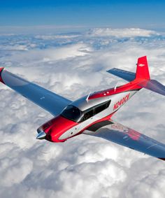 a red and white airplane flying above the clouds