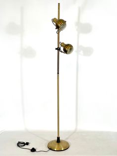 a floor lamp with three lights on it and a cord attached to the base that is plugged in