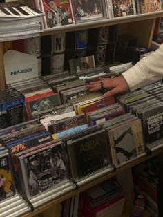 a man standing in front of a shelf filled with cds