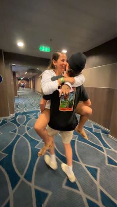 two people hugging each other while standing on a blue carpeted floor in an elevator