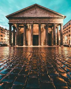 an old building with columns and pillars in front of it at dusk, lit up by street lights