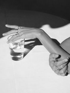 two people holding hands over a glass of water