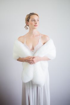 a woman wearing a white dress and fur stole