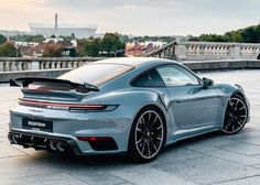 a grey sports car parked in front of a building with a view of the eiffel tower