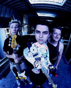 three young men are holding guitars and posing for the camera