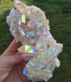 a person holding some kind of crystal rock in their hand with grass behind it on the other side