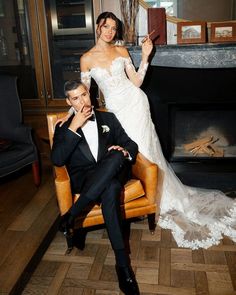 a bride and groom posing for a photo in front of a fireplace